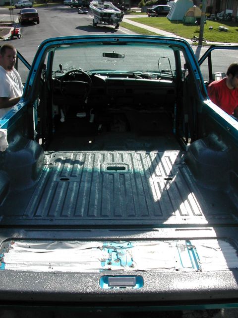 1994 Ford Bronco - The interior and bed of a teal Ford F-Series truck are shown, with two men standing nearby.