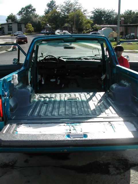 1994 Ford Bronco - The interior and bed of a teal pickup truck are visible with the tailgate down, suggesting preparation for work or transport.