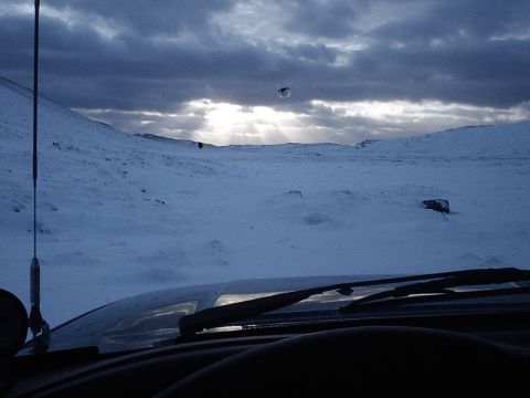 1996 Ford Bronco - Driving through a snowy landscape under a dramatic sky.