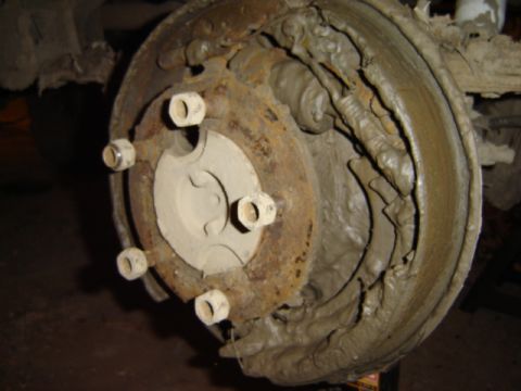 1992 Ford Bronco - A close-up view of a heavily soiled drum brake assembly, showing significant rust and mud accumulation.