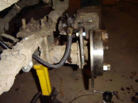1992 Ford Bronco - Vehicle brake assembly with rotor and caliper, supported by a jack.