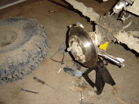 1992 Ford Bronco - A vehicle's axle and tire are shown disassembled on a jack stand, with tools scattered nearby.