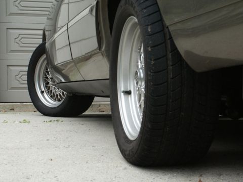2001 Mercury Grand Marquis - Close-up side view of a car's tires and lower body panels, chrome wire wheels.