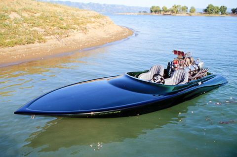 1991 Ford Bronco - A powerful speed boat with a large engine sits on the water near a sandy shore.