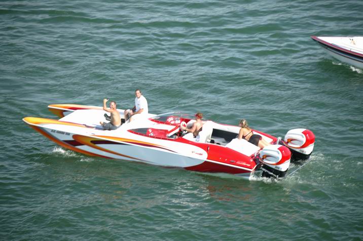 Red and white speedboats with people on board, one with dual outboard motors