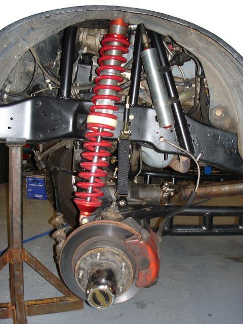 1987 Ford Bronco - Close-up of a vehicle's modified suspension system, showing a red coilover shock and brake components.