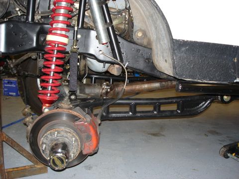1987 Ford Bronco - Close-up view of the modified suspension system, red coilover shocks and aftermarket rock sliders.