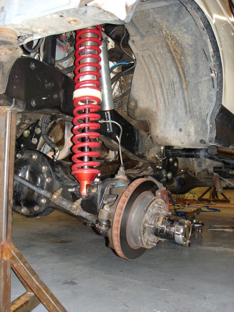 1987 Ford Bronco - Close-up of a vehicle's front suspension and differential, a red coilover shock absorber.