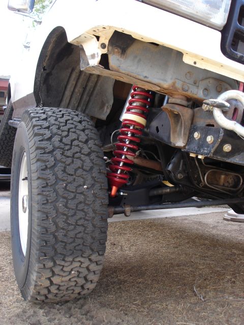 1987 Ford Bronco - This photo shows the front suspension of a vehicle, focusing on the coilover shock and tire, not the entire vehicle.