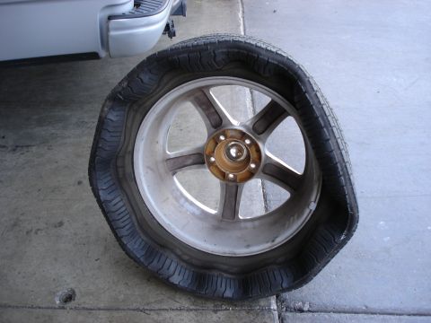 2003 Ford F-150 - A flat tire is shown on a vehicle, with the rim and part of the vehicle's body visible.