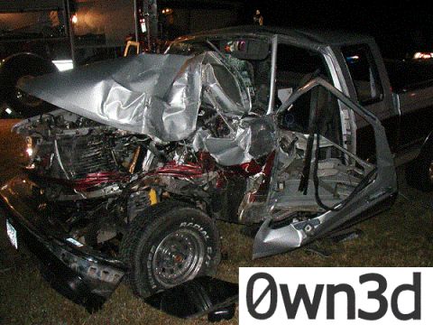 1985 Ford Bronco - Night photo of a severely wrecked silver extended-cab pickup with the front end crushed back to the firewall, hood buckled, driver's door t…
