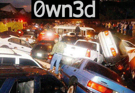 Nighttime pile of dozens of cars and pickups stacked together with onlookers