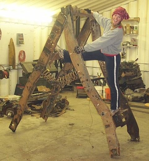 1990 Ford Bronco - A person poses on a large, rusty A-frame structure with visible springs, likely a salvaged vehicle part.