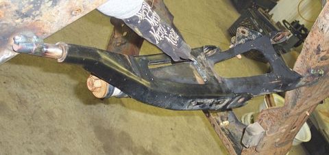 1990 Ford Bronco - Close-up view of a vehicle's suspension component, with a gloved hand interacting with it.