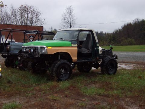 1978 Ford Bronco - A heavily modified pickup truck sits outdoors next to another off-road vehicle under a cloudy sky.