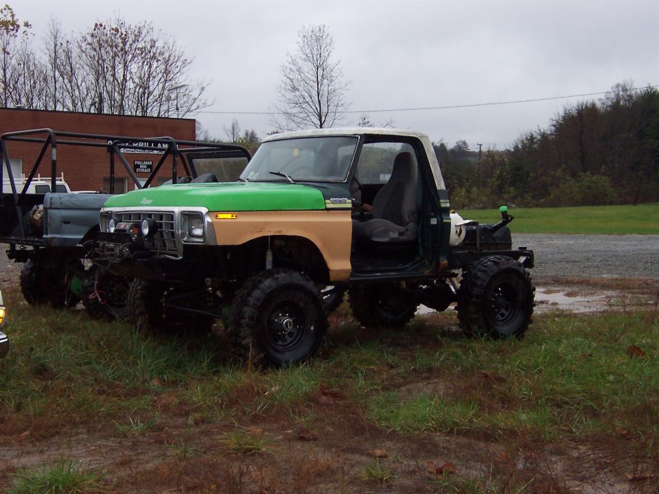 Lifted green and tan Ford Bronco with doors removed, parked on grass