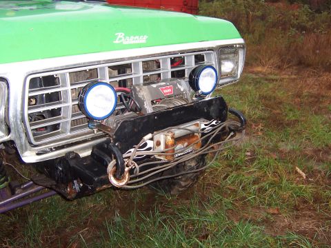 1978 Ford Bronco - The front of a green 1978 Ford Bronco shows a prominent grille, a winch, and auxiliary lights.