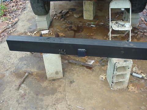 1988 Ford Bronco - A black metal bumper is supported by cinder blocks and a concrete slab, with a vehicle tire visible in the upper left.
