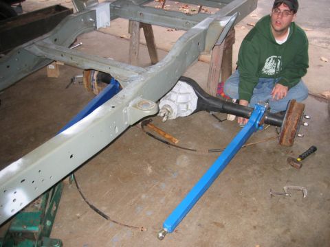 1978 Ford Bronco - A person works on a vehicle's frame and rear axle in a garage setting.