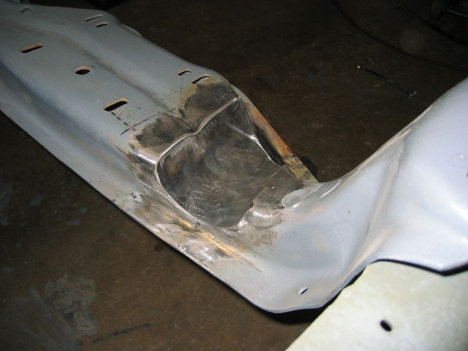 Gray metal vehicle frame section with cutouts and weld marks