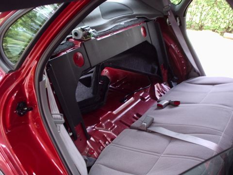 1998 Ford Taurus - The rear interior of a red vehicle is shown with the seats removed, revealing the exposed metal floor and wiring harness.