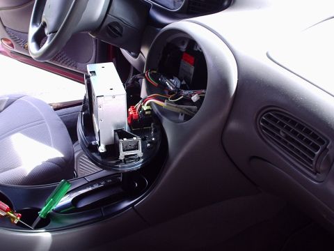 1998 Ford Taurus - Interior shot of a gray oval-styled dashboard with the center radio bezel removed, exposing the empty head-unit cavity and a bundle of fact…