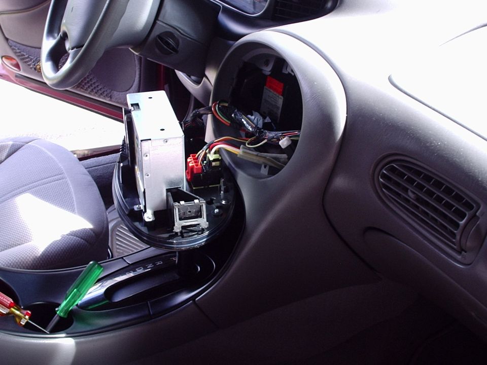 Gray dashboard with radio bezel removed exposing wiring harness and pulled head unit
