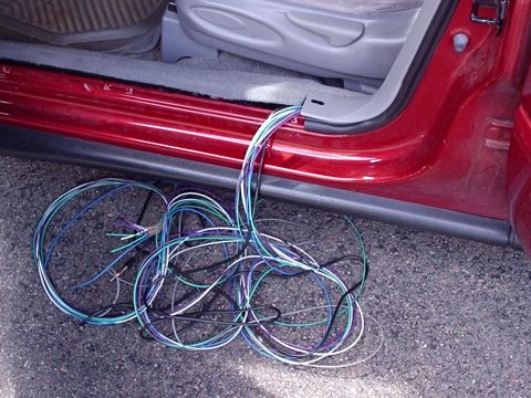 1998 Ford Taurus - A bundle of multicolored wires is visible emerging from the door frame of a red vehicle.