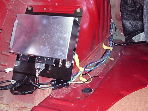 1998 Ford Taurus - A close-up view of aftermarket wiring and an electronic module installed in the interior of a red vehicle.