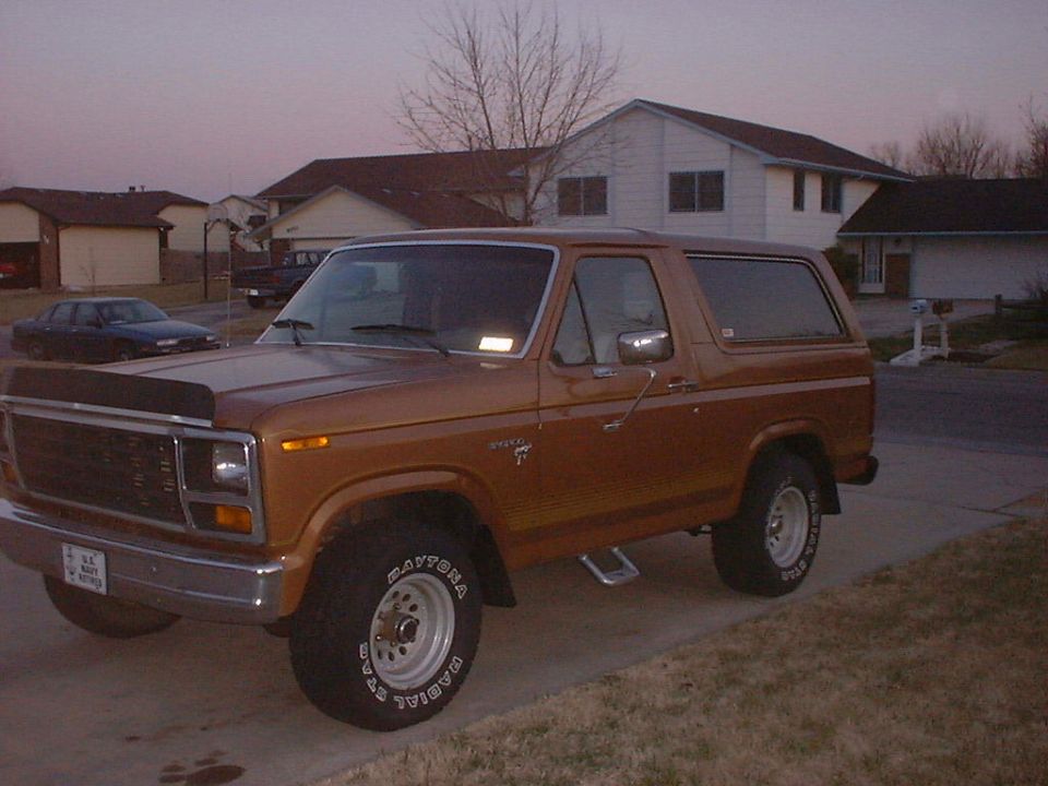 Brown Ford Bronco parked in a driveway, front quarter view. Has a license plate and "Bronco" badging