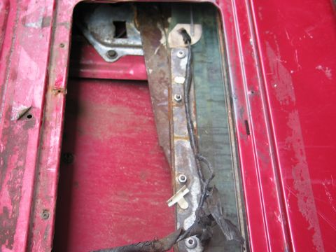 1995 Ford Bronco - Interior view of a red car door, revealing the window regulator assembly and associated wiring.