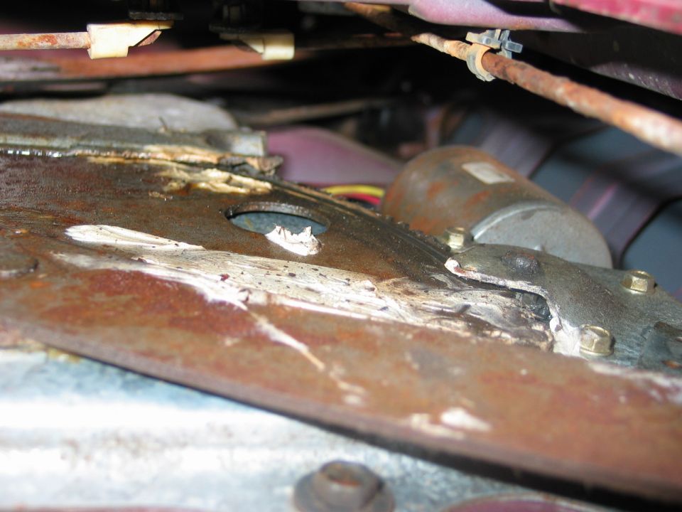 Rusty vehicle frame rail with fresh weld repair seen from underneath