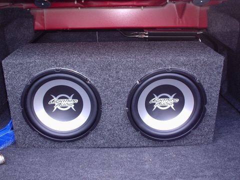 1998 Ford Taurus - A pair of Lightning Audio subwoofers are installed in a carpeted enclosure in the trunk of a vehicle.