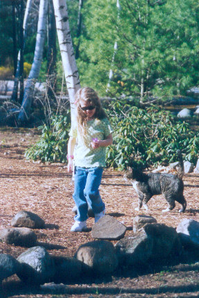 1991 Ford Bronco - A young girl and a cat are in a natural outdoor setting with trees and rocks.