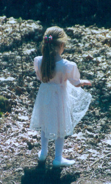 1991 Ford Bronco - A young girl in a white dress and tights stands in a natural outdoor setting.