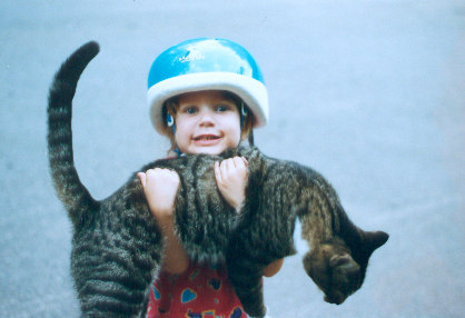 1991 Ford Bronco - A child poses with a cat, wearing a helmet and a red patterned dress.