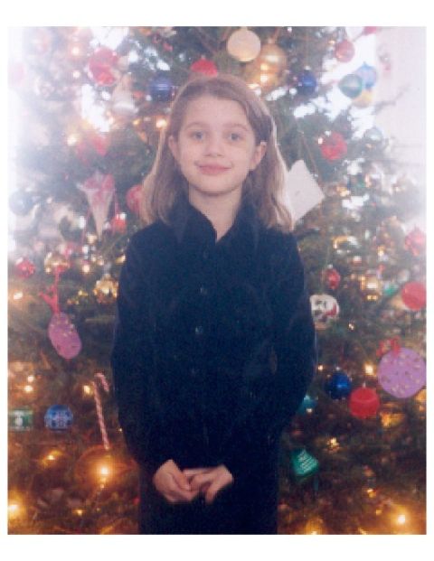 1991 Ford Bronco - A child poses for a photo in front of a Christmas tree adorned with ornaments and lights.