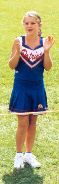 1991 Ford Bronco - A young cheerleader in a blue skirt and 'Patriots' top claps her hands while standing on a grassy field.