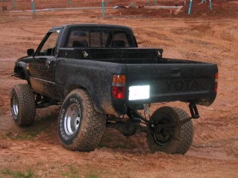 1986 Ford F-150 - This black Toyota pickup truck has a lifted suspension and large off-road tires.