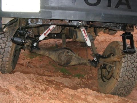 1986 Ford F-150 - Close-up of a vehicle's rear suspension and axle assembly, showing aftermarket shocks and leaf springs.