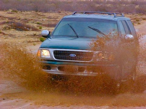 1997 Ford Expedition - This Ford Expedition is kicking up a lot of mud as it drives through a wet, unpaved area.