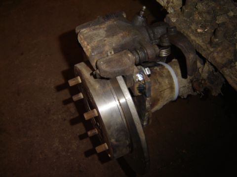 1992 Ford Bronco - Close-up view of a vehicle's brake caliper and rotor assembly, showing the disc brake and mounting hardware.