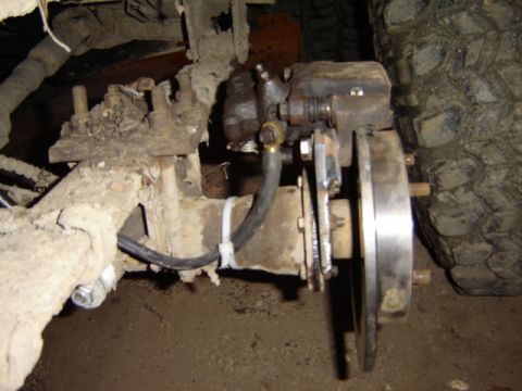 1992 Ford Bronco - Vehicle brake system component, likely a rear caliper and rotor, showing signs of wear and dirt.