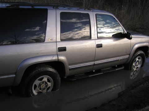 2000 Chevrolet Tahoe - This silver SUV appears to be stuck in a muddy area, with its front wheel submerged.