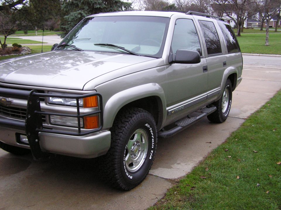 Silver SUV with a black brush guard on the front. It has running boards and all-terrain tires