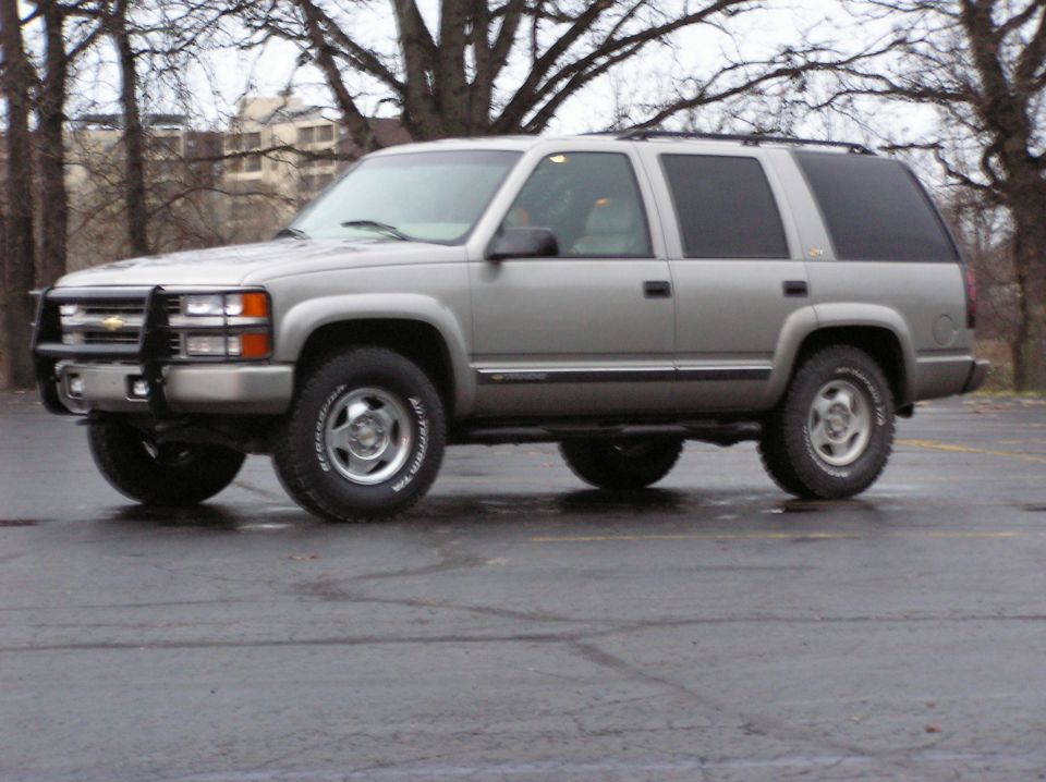 Silver SUV with a black bull bar and tinted windows, parked on wet asphalt
