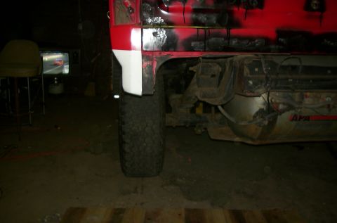 1981 Ford Bronco - The rear quarter panel of a 1981 Ford Bronco shows red and white paint with visible rust and damage.