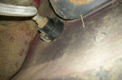 1981 Ford Bronco - Close-up view of the underside of a vehicle, focusing on a rubber grommet and hose assembly.
