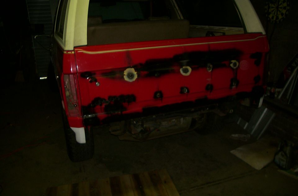 1981 Ford Bronco rear gate being prepped for paint, showing red primer and black primer spots