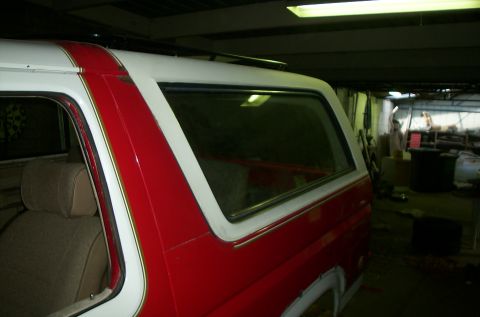 1981 Ford Bronco - A red and white SUV is parked inside a garage, with a partial view of its interior and roof.